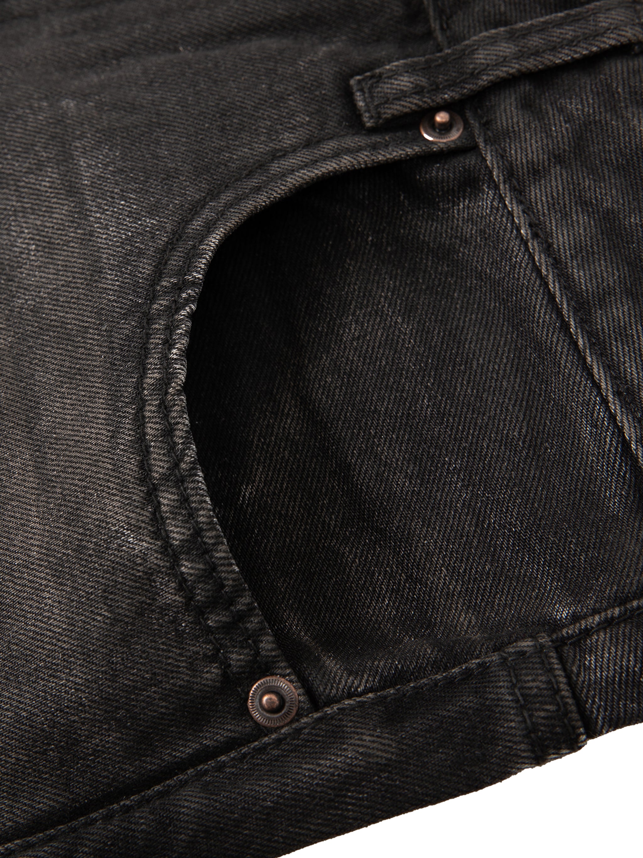 Close-up of vintage wash black heavyweight denim jeans showing pocket detail and copper-toned metal rivets.